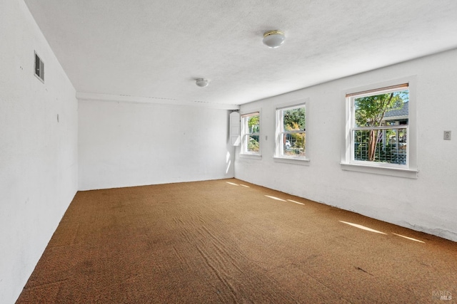 carpeted spare room featuring visible vents and a textured ceiling