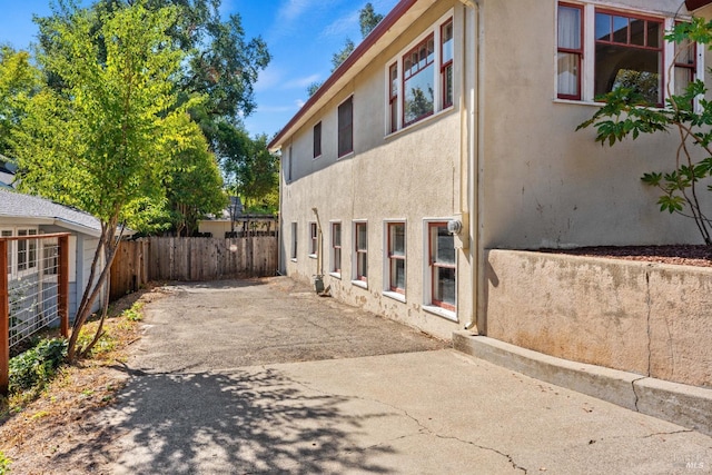 view of home's exterior with fence, a patio, and stucco siding