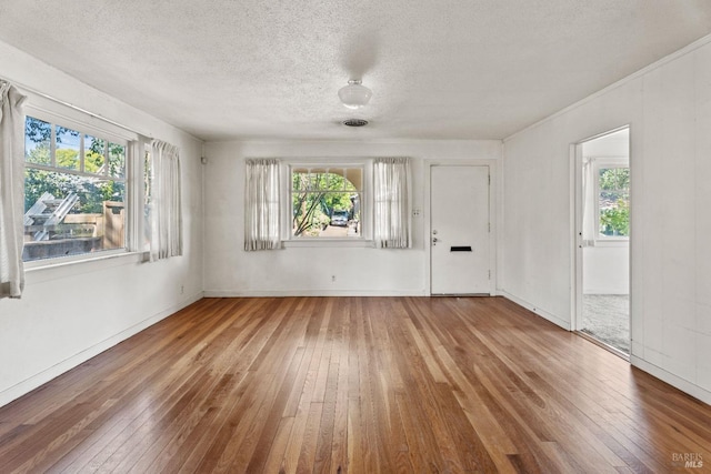 unfurnished room with a healthy amount of sunlight, hardwood / wood-style flooring, and a textured ceiling