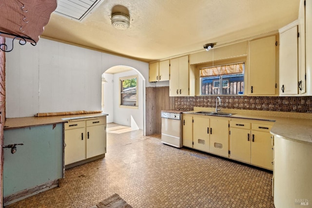 kitchen featuring range, arched walkways, cream cabinetry, and a sink