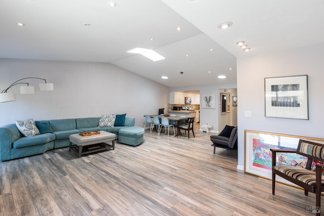 living room featuring lofted ceiling with skylight and wood-type flooring