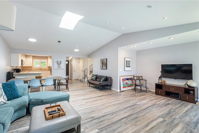 living room featuring light hardwood / wood-style flooring, lofted ceiling with skylight, and sink