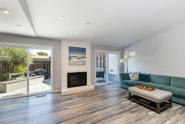 living room with wood-type flooring and a brick fireplace