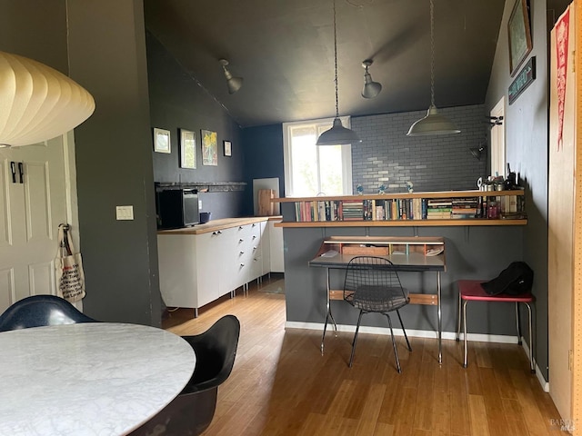 kitchen featuring lofted ceiling, decorative light fixtures, hardwood / wood-style floors, and backsplash