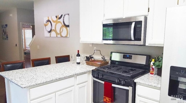 kitchen with light stone countertops, stainless steel appliances, and white cabinets