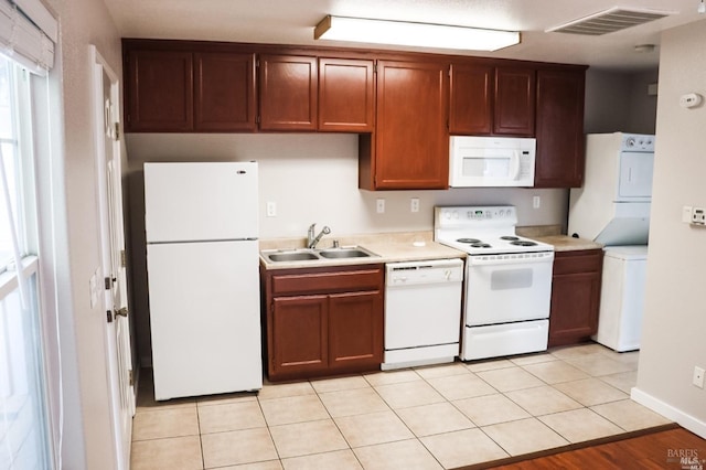 kitchen with light hardwood / wood-style flooring, sink, white appliances, and stacked washing maching and dryer