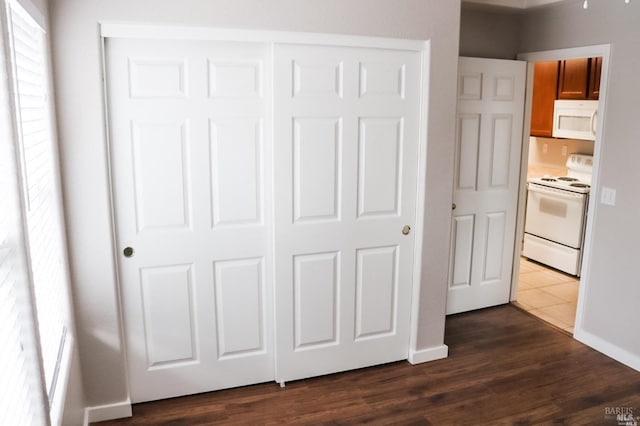 unfurnished bedroom with a closet, dark hardwood / wood-style flooring, and multiple windows