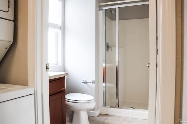 bathroom featuring tile patterned floors, toilet, a shower with door, and vanity