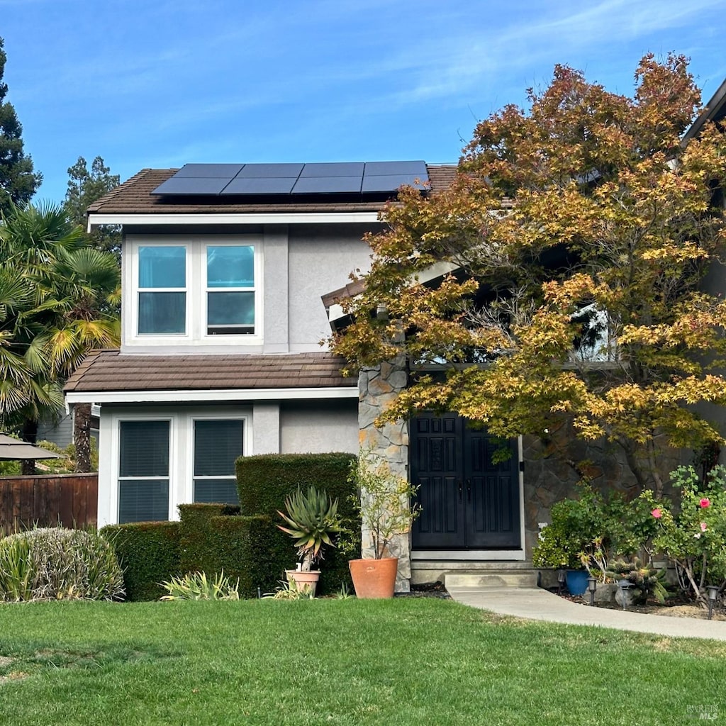 view of front of property featuring solar panels and a front yard