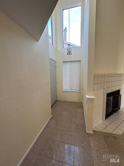 unfurnished living room with a towering ceiling and a tiled fireplace