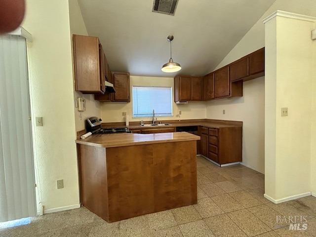 kitchen featuring vaulted ceiling, sink, stainless steel stove, and decorative light fixtures