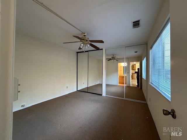 unfurnished bedroom with two closets and ceiling fan