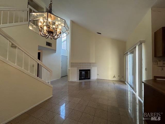 unfurnished living room with a fireplace, a chandelier, and a high ceiling