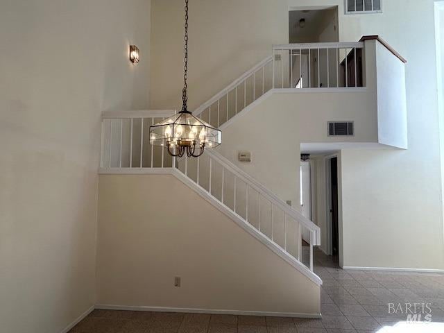 staircase with an inviting chandelier and a towering ceiling