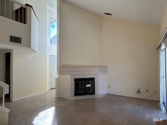 unfurnished living room with a fireplace and a high ceiling