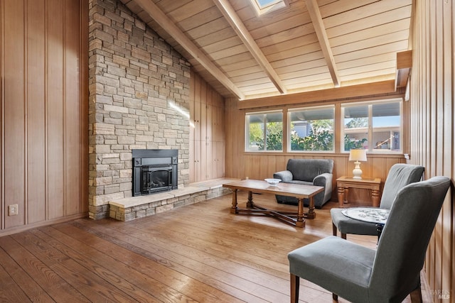 living area featuring wood ceiling, light wood-type flooring, wooden walls, beamed ceiling, and a fireplace