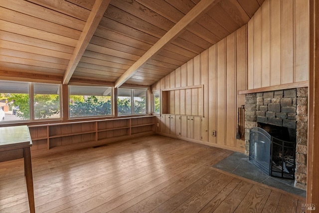 unfurnished sunroom with a healthy amount of sunlight, vaulted ceiling with beams, wood ceiling, and a fireplace