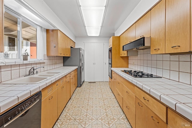 kitchen featuring stainless steel appliances, tile counters, sink, and backsplash