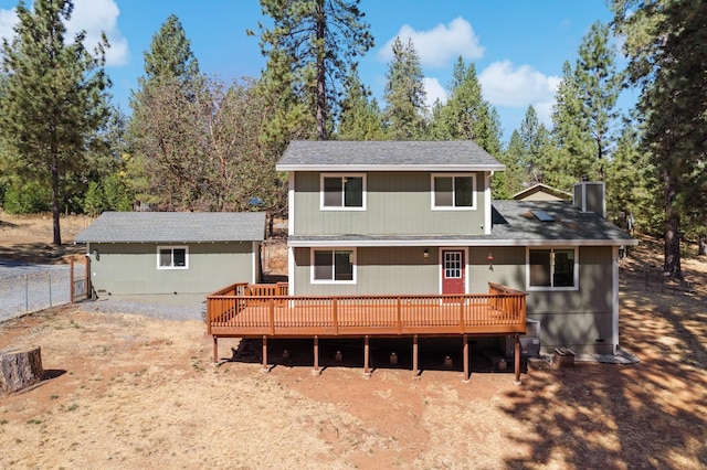 rear view of house with fence and a deck