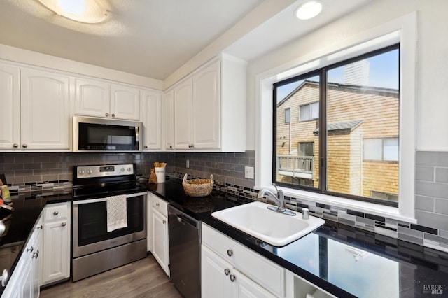 kitchen featuring hardwood / wood-style floors, appliances with stainless steel finishes, white cabinetry, and sink