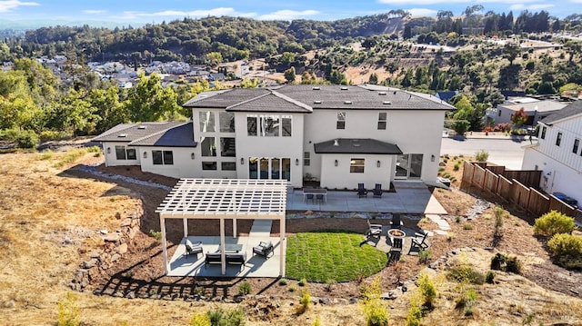 back of house featuring an outdoor living space with a fire pit, fence, and a patio