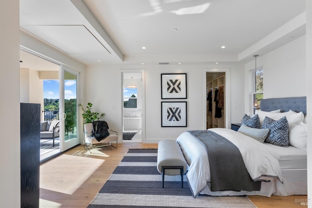 bedroom with access to exterior, a walk in closet, ensuite bath, hardwood / wood-style flooring, and a closet