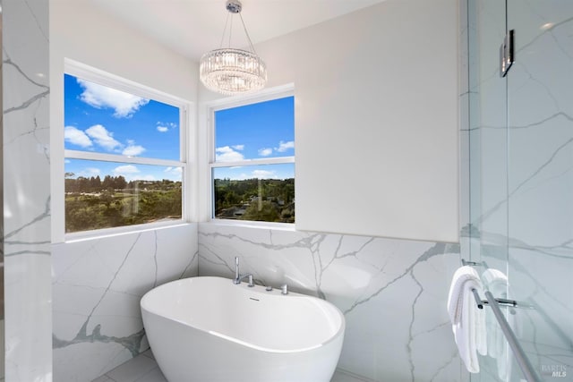 bathroom with a bathing tub, a notable chandelier, and tile walls