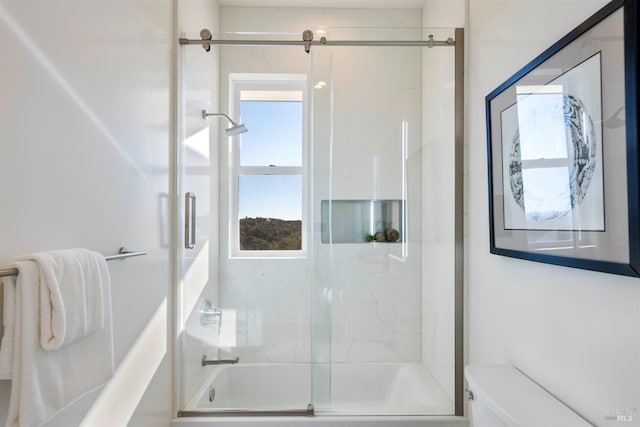 bathroom featuring bath / shower combo with glass door and toilet