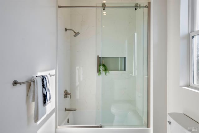 bathroom featuring bath / shower combo with glass door and toilet