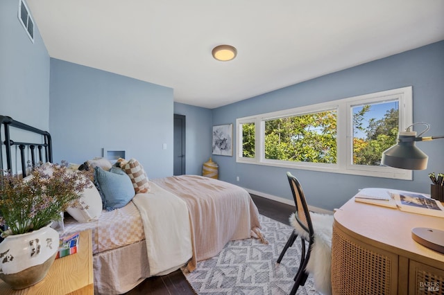 bedroom with wood finished floors, visible vents, and baseboards