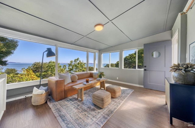 sunroom with lofted ceiling and a water view