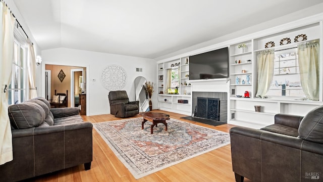 living room with vaulted ceiling, a fireplace, and hardwood / wood-style floors