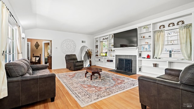 living room with wood-type flooring, lofted ceiling, and a fireplace