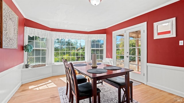 dining room with a healthy amount of sunlight, crown molding, wood-type flooring, and french doors