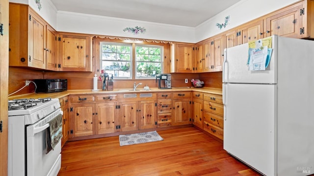 kitchen with crown molding, white appliances, sink, and light hardwood / wood-style flooring