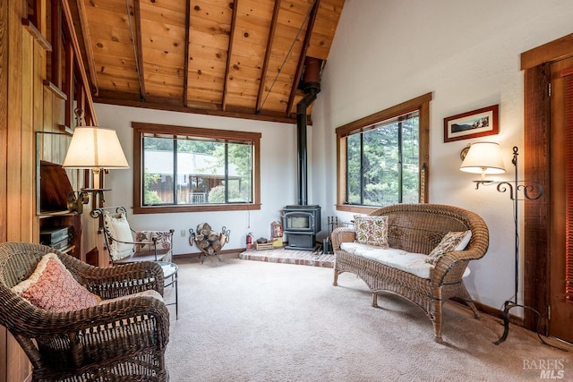 living area with vaulted ceiling with beams, a wood stove, carpet, and wood ceiling