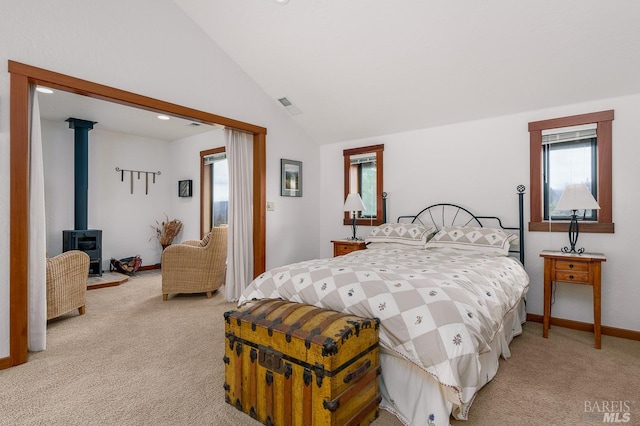 carpeted bedroom with vaulted ceiling, a wood stove, and multiple windows