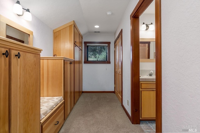 corridor with light carpet, a textured ceiling, and vaulted ceiling