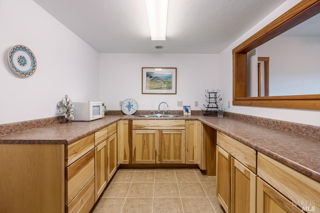 kitchen featuring kitchen peninsula, a textured ceiling, light tile patterned flooring, and sink