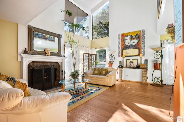 living room with hardwood / wood-style floors, a fireplace, and a high ceiling