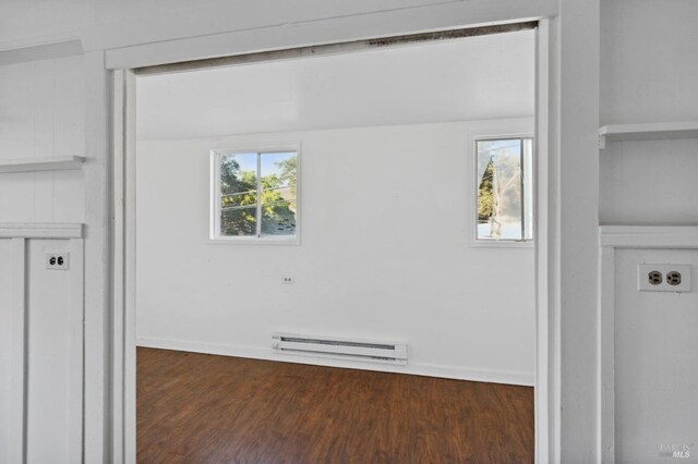 interior space featuring baseboard heating, dark hardwood / wood-style floors, and a healthy amount of sunlight