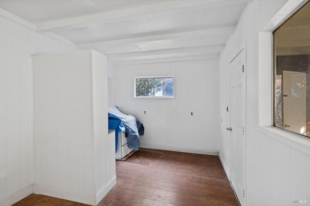 unfurnished bedroom with beamed ceiling, wooden walls, and dark wood-type flooring