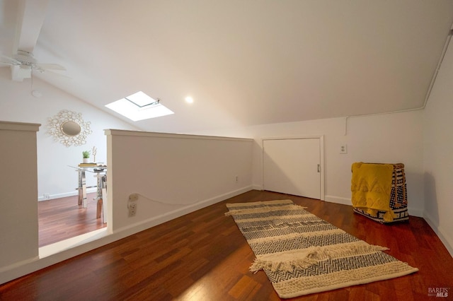 additional living space with vaulted ceiling with skylight, ceiling fan, and dark wood-type flooring