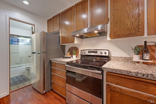 kitchen featuring appliances with stainless steel finishes, light stone countertops, and light hardwood / wood-style flooring