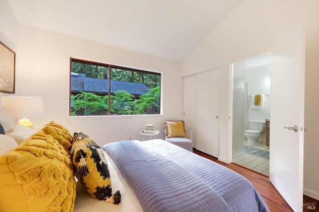 bedroom featuring wood-type flooring, ensuite bath, and vaulted ceiling