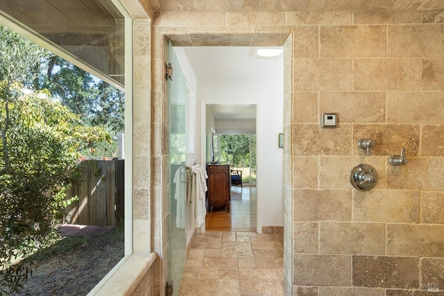 bathroom featuring a tile shower and stone tile flooring