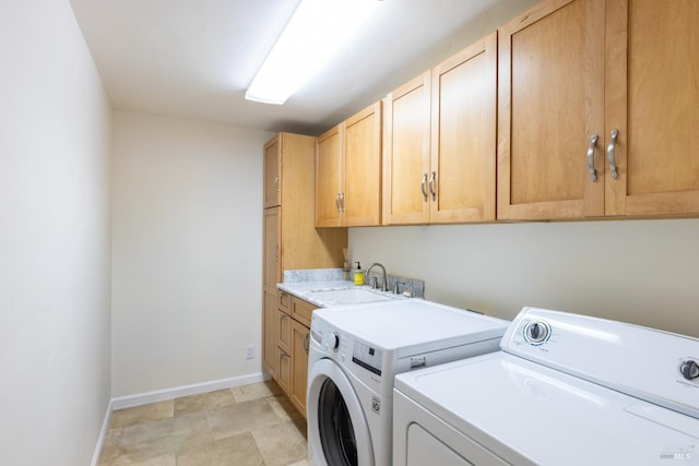 washroom featuring a sink, washer and clothes dryer, cabinet space, and baseboards