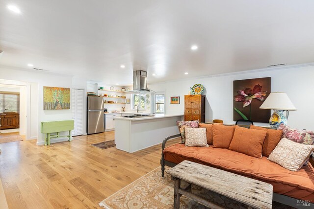 living room with light wood-style flooring, ornamental molding, visible vents, and recessed lighting