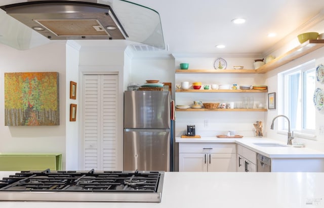 kitchen featuring a sink, ornamental molding, freestanding refrigerator, gas stovetop, and white cabinetry