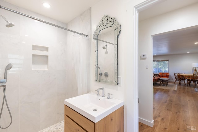 bathroom featuring recessed lighting, tiled shower, vanity, and wood finished floors
